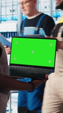 Dikey video akıllı fabrika teknisyeni robot kolları kontrol ediyor. Model defter kullanarak, kapat. Sektör 4.0 endüstriyel santraldeki mühendis otomatik makineleri yeşil ekran dizüstü bilgisayar ve kamera A kullanarak kontrol ediyor.