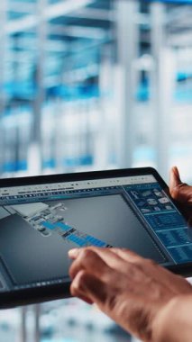 Dikey video endüstrisi 4.0 endüstriyel fabrika mühendisi tablet üzerinde CAD yazılımı kullanarak yeni robotik makineler tasarlıyor. Otomasyon için dijital aygıt uygulaması kullanan akıllı bir fabrika teknisyeni