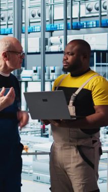 Stajyer doktorla akıllı fotovoltaik fabrikası konuşmalarında sistem performans ölçümlerini gösteren dikey video mühendisi. Deneyimli güneş panelleri enerji takibi konusunda yeni stajyere rehberlik ediyor.