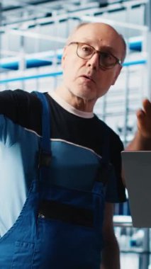 Dikey video akıllı fabrika mühendisi yeni stajyere robotik silah kullanmayı öğretiyor. Endüstri 4.0 Endüstriyel Sanayi Ekibi lideri ve stajyer otomatik makineleri kontrol ederek iş akışını sağlıyorlar