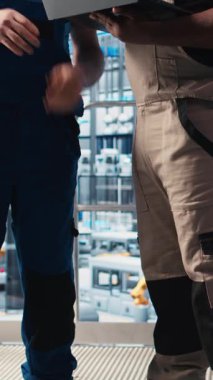Dikey video akıllı fabrika mühendisi yeni stajyere robotik silah kullanmayı öğretiyor. Endüstri 4.0 Endüstriyel Sanayi Ekibi lideri ve stajyer otomatik makineleri kontrol ederek iş akışını sağlıyorlar