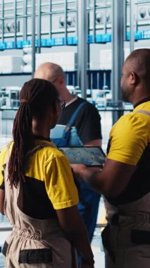 Dikey video endüstrisi 4.0 endüstriyel fabrika mühendisliği ekibi tablet üzerinde CAD uygulaması kullanarak yeni robotik makineler tasarlıyor. Takım çalışması akıllı fabrika çalışanları otomasyon ekipmanları, kamera programlıyorlar.