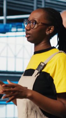 Endüstrideki dikey video mühendisliği ekibi 4.0 endüstriyel fabrikada makineleri kurmak için işbirliği yapıyorlar, monitöre bakıyorlar. Takım çalışması zeki fabrika meslektaşları IoT sensörlerini ayarlamak için beyin fırtınası yapıyorlar.