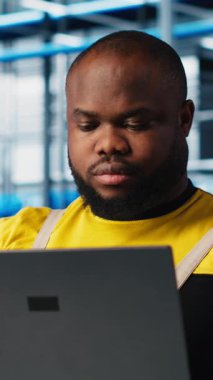 Sektör 4.0 endüstriyel fabrikadaki gülen mühendis bilgisayarla otomatik makineleri kontrol ederek iş akışının devamlılığını sağlıyor. Mutlu akıllı fabrika teknisyeni robot kolları kullanıyor.