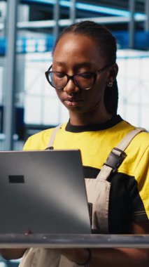 Dikey video akıllı fabrika mühendisi tesis katındaki robotik silah ve taşıma sistemlerini denetliyor. Sanayi 4.0 fabrika teknisyeni sistem performansını izliyor ve sorun yaratıyor