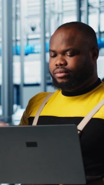 Dikey video Photovoltaics akıllı fabrika lideri stajyere bilgisayarla hasarlı IOT sensörlerini nasıl tamir edeceğini öğretiyor. Sanayi 4.0 güneş panelleri. Bitki, stajyer mühendisleri azaltma konusunda deneyimli.