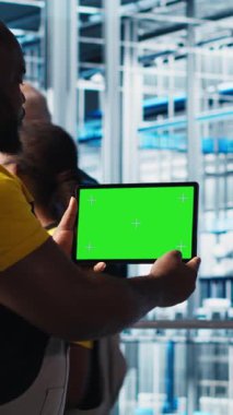 Dikey video akıllı fabrika mühendisi, yeşil ekran tablet kullanan robotik silah ve taşıma bantlarının çalışmasını denetliyor. Sektör 4.0 bitki teknisyeni krom anahtar aygıtı kullanılarak sistem performansını izler