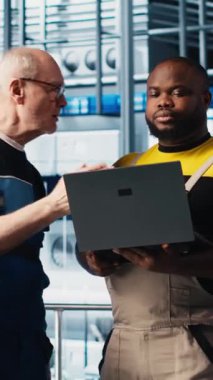 Stajyer doktorla akıllı fotovoltaik fabrikası konuşmalarında sistem performans ölçümlerini gösteren dikey video mühendisi. Deneyimli güneş panelleri enerji takibi konusunda yeni stajyere rehberlik ediyor.