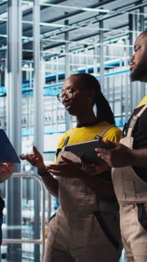 Dikey video endüstrisi 4.0 fotovoltaik tesisi kıdemli mühendis enerji üretimini maksimuma çıkarmak için işçilerle kağıt okuma görüşmeleri yapıyor. Güneş panelleri. Akıllı fabrika yöneticileri görev verme konusunda tecrübeli.