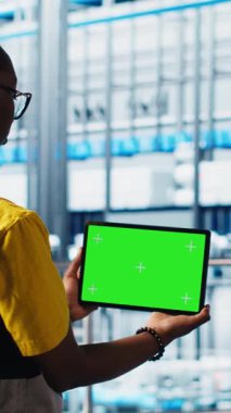 Dikey video akıllı fabrika uzmanı otomatik sistemleri test etmek ve güvenilirliği sağlamak için dizüstü bilgisayar kullanıyor. Kadın dar geçitleri tanımlamak ve ekipmanları ve kamerayı optimize etmek için izole ekran defteri kullanır