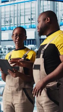 Dikey video Photovoltaics akıllı fabrika personeli tablet kullanarak PV materyallerini araştırıyor. Sanayi 4.0 güneş panelleri Afro-Amerikan mühendisleri alternatif enerji sistemleri geliştiriyor