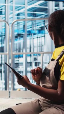 Dikey video endüstrisi 4.0 endüstriyel fabrika uzmanı tablet kullanarak otomatikleştirilmiş makineleri kontrol ediyor ve iş akışının devamlılığını sağlıyor. Akıllı fabrika çalışanı robotik silah ve taşıma bantları ile yönetiyor