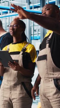 Dikey video akıllı fabrika çalışanları konuşuyor, otomatik sistemleri test etmek için birlikte çalışıyorlar. Endüstri 4.0 endüstriyel fabrika çalışma arkadaşları dar boğazları tespit etti ve verilere dayanarak ekipmanları optimize etti