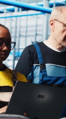 Dikey video mühendisleri, toplanan ölçümleri gösteren akıllı fabrika yöneticisiyle konuşuyor. Teknisyenler, sensörlerle donatılmış sanayi 4.0 sanayi fabrikasındaki denetçiden geri bildirim alıyorlar.