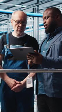 Dikey video mühendisleri, toplanan ölçümleri gösteren akıllı fabrika yöneticisiyle konuşuyor. Teknisyenler, sensörlerle donatılmış sanayi 4.0 sanayi fabrikasındaki denetçiden geri bildirim alıyorlar.