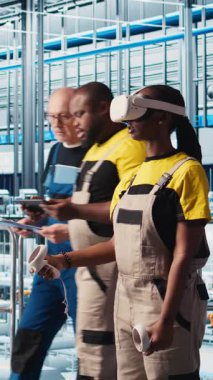 VR kulaklık takan dikey video Smart fotovoltaics fabrika uzmanı sistem performans ölçümlerine bakıyor. Güneş panelleri fabrika işçisi IOT aracılığıyla enerji üretimini izlemek için sanal gerçeklik teknolojisi kullanıyor