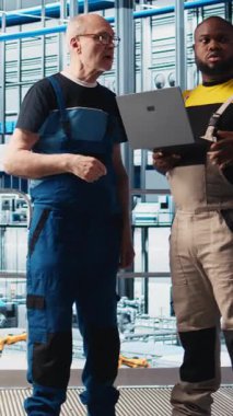 Dikey video akıllı fabrika kıdemli mühendisi stajyere otomatik iş akışlarını uygulamayı ve elle işlemleri bilgisayara geçirmeyi öğretiyor. Tecrübeli bir adam stajyerin sensörleri üretime ve kameraya entegre etmesine yardım ediyor.