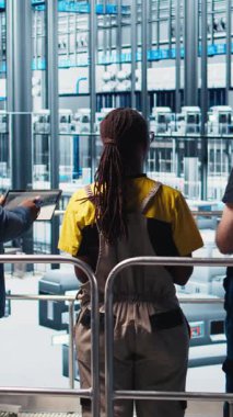 Dikey video yöneticisi sektör 4.0 endüstriyel fabrikayı denetliyor CAD yazılımı kullanarak makine dizayn eden işçilere talimatlar veriyor. Akıllı fabrika yöneticisi mühendislere otomasyon geliştirme görevi verdi