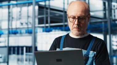 Akıllı fabrika kıdemli mühendisi, robotik silah ve taşıma sistemlerini denetlemek için dizüstü bilgisayar kullanır. Deneyimli sanayi 4.0 bitki teknisyeni sistem performansını not defteri, kamera A kullanarak gözlemliyor.