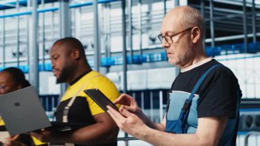 Tabletteki sistem performans ölçümlerine bakan akıllı fotovoltaik fabrikasında kıdemli mühendis. Deneyimli güneş panelleri IoT sensörleri aracılığıyla enerji üretimini izleyen fabrika işçisi, kamera A