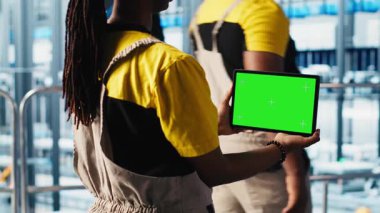 Akıllı bir fabrika teknisyeni robot kolları kontrol ediyor. Model defter kullanarak, kapat. Sektör 4.0 endüstriyel santraldeki mühendis otomatik makineleri yeşil ekran dizüstü bilgisayar ve kamera A kullanarak kontrol ediyor.