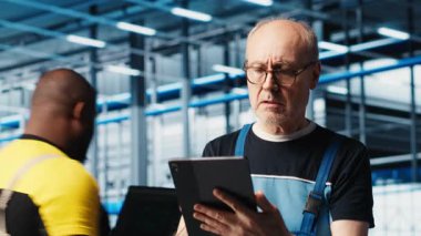 Akıllı güneş panelleri imalat fabrikasındaki yaşlı kıdemli mühendis güç üretimini maksimuma çıkarmak için tablet üzerinde yazılım kullanıyor. Deneyimli profesyonel denetim sektörü 4.0 fotovoltaik fabrikası, kamera A