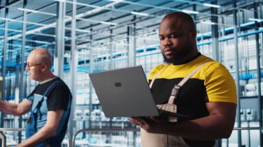 Sektör 4.0 'daki gülümseyen mühendis otomatik makineleri kontrol ederek iş akışının devamlılığını sağlıyor. Happy akıllı fabrika teknisyeni robot kolları idare ediyor. Not defteri, kamera A kullanarak.