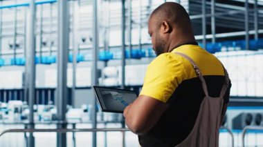 Endüstri 4.0 endüstriyel fabrika uzmanı tablet üzerindeki CAD programını kullanarak yeni robotik makineler tasarlıyor. Afrika kökenli Amerikalı bir adam akıllı fabrikada otomasyon ekipmanları için cihaz kullanıyor. Kamera A