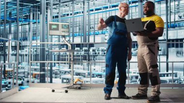 Kıdemli mühendis akıllı fabrikada stajyerlerle konuşuyor, veri topluyor ve analiz ediyor. Tecrübeli teknisyen, stajyerin takip yazılımını kullanmasına yardım ediyor. Endüstriyel tesiste sensörlerle donatılmış, kamera A