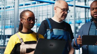 Mühendisler akıllı fabrika yöneticisiyle konuşuyor, ölçümleri gösteriyor. Teknisyenler, sensörleri ve kamera A ile donatılmış sanayi 4.0 sanayi tesisinin yöneticisinden geri bildirim alıyorlar.