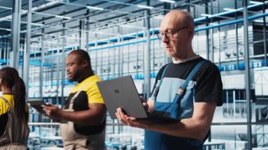 Akıllı fabrika kıdemli mühendisi, robotik silah ve taşıma sistemlerini denetlemek için dizüstü bilgisayar kullanır. Deneyimli sanayi 4.0 bitki teknisyeni sistem performansını not defteri, kamera A kullanarak gözlemliyor.