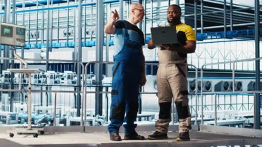 Kıdemli mühendis akıllı fabrikada stajyerlerle konuşuyor, veri topluyor ve analiz ediyor. Tecrübeli teknisyen, stajyerin takip yazılımını kullanmasına yardım ediyor. Endüstriyel tesiste sensörlerle donatılmış, kamera A