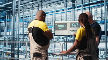 Akıllı fotovoltaik fabrikası çalışanları sistem performans ölçümlerine bakarak beyin fırtınası yapıyorlar. Güneş panelleri, IoT sensörleri ve kamera A aracılığıyla enerji üretimini tartışıyor, takip ediyor.