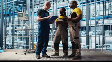 Photovoltaics akıllı fabrika ekip lideri ve verileri analiz eden işçiler. Endüstrideki kıdemli mühendis ve iş arkadaşları 4.0 güneş panelleri fabrika yenilenebilir enerji değerlendirme ölçümleri, kamera A