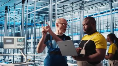 Fotovoltaik zeki fabrika lideri stajyere bilgisayarla hasar görmüş IOT sensörlerini nasıl onaracağını öğretiyor. Endüstri 4.0 güneş panelleri. Bitki fabrikası, stajı azaltma konusunda tecrübeli mühendis rehberi, kamera A