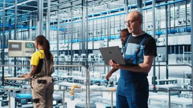 4.0 endüstriyel fabrika kıdemli mühendisi dizüstü bilgisayar yazılımı kullanarak robot makineleri otomatikleştiriyor. Deneyimli teknisyen akıllı fabrikada yapay zeka özelliklerini not defteri, kamera A kullanarak uyguluyor.