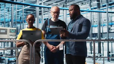 Mühendisler akıllı fabrika yöneticisiyle konuşuyor, ölçümleri gösteriyor. Teknisyenler, sensörleri ve kamera A ile donatılmış sanayi 4.0 sanayi tesisinin yöneticisinden geri bildirim alıyorlar.