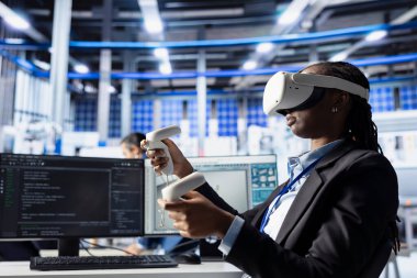 Güneş panelleri performans verilerini analiz eden fabrika işçisi, VR ekipmanları kullanarak verimliliği optimize ediyor. Fotovoltaik fabrikasındaki kadın sanal gerçeklik teçhizatı kullanarak güneş pilleri tasarım prototipi üzerinde çalışıyor.