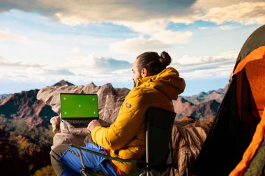 Macera Avcısı, izole edilmiş krom anahtarın yanındaki dağın zirvesinde duruyor ve önünde durmaksızın uzanan manzara manzarasına bakıyor. Temiz hava ve nefes kesici manzara..