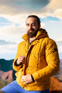 Macera arayıcısının portresi dağın zirvesine ulaşıyor ve manzaraya hayran kalıyor, vadi manzarasını ve doğanın vahşi doğasını seviyor. Yürüyüşün ve gezinin tadını çıkaran bir yürüyüşçü..