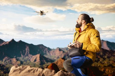 Genç doğa aşığı fotoğrafçı, dağ vadisinde uzaktan kumandalı yüksek kaliteli içerikli bir video bloğu aracılığıyla yaptığı yürüyüş yolculuğunu İHA ile kaydediyor. Yürüyüşçü manzarayı filme alıyor..