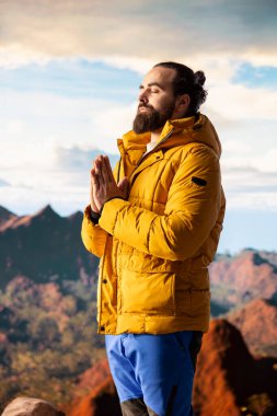 Keyifli bir doğa aşığı dağ sırasının tepesinde meditasyon yapıyor, meditasyon yapıyor ve rahatlık ve zihinsel berraklık için derin nefesler alıyor. Huzurlu zen yürüyüşçüsü tırmanmayı sever.