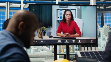 Ofisteki yöneticiler internet video görüşmesi sırasında güneş teknolojisi raporlarını inceliyorlar. Uzak telekonferans toplantısındaki hissedarlar yeşil enerji üretimindeki yatırım fırsatlarını tartışıyorlar, kamera B