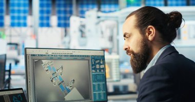 Fotovoltaik fabrikası teknisyeni sistem parametrelerini güneş pillerinin enerji üretimini maksimuma çıkarmak için dizüstü bilgisayara ayarlar. Güneş paneli imalat tesisinde enerji kaynağını optimize eden defter kullanan adam, kamera B