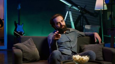 Televizyon ekranındaki kanalları değiştirmek için uzaktan kumanda kullanan bir adam ilginç olmayan içerikten bıkmış hisseder. Televizyon kanallarında gezinen sıkkın insan izlenecek bir şey bulamayınca üzülüyor. Kamera A.