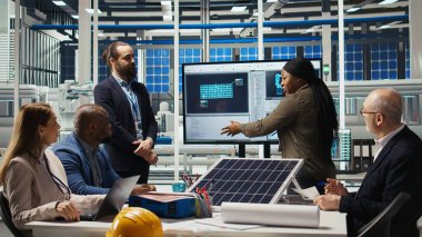 Fotovoltaik bitki araştırmacıları toplanıyor, monitörlere bakıyor, enerji üretimini arttırmak için güneş hücrelerini değerlendiriyor. Uzmanlar daha iyi enerji emilimi için fabrika ekipmanlarını optimize ediyorlar, kamera A