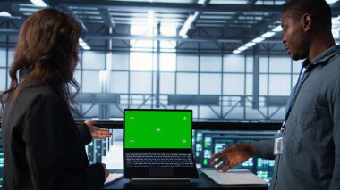 Veri merkezi sistem yöneticileri ekipman teşhislerini gözden geçirmek için dizüstü bilgisayar kullanıyorlar. Ekip çalışması bilişim uzmanları sunucu çiftliği ayarlarını kroma anahtar defteri kullanarak ayarlıyorlar