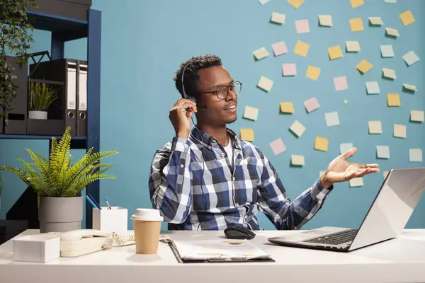 Tele pazarlamacı masada oturuyor ve başvuru belgeleri için bir müşteriye telefonda yardım ediyor. Şirket danışmanı laptopunu kullanıyor ve bir telefon görüşmesi yapıyor, çalışana yardım sağlıyor..