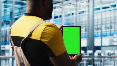 Otomatik sistemleri test etmek ve güvenilirliği sağlamak için yeşil ekran tableti kullanan akıllı bir fabrika uzmanı. İşçi, dar boğazları tanımlamak ve sensör verilerine dayanarak donanımı optimize etmek için krom anahtar aygıtı kullanır, kamera A