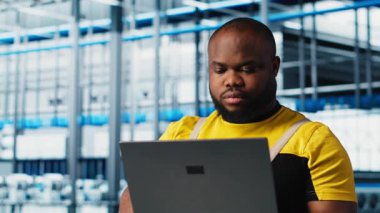 Sektör 4.0 'daki gülümseyen mühendis otomatik makineleri kontrol ederek iş akışının devamlılığını sağlıyor. Happy akıllı fabrika teknisyeni robot kolları idare ediyor. Not defteri, kamera A kullanarak.